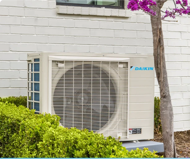 Daikin FIT installed beside a white brick home with landscaped garden