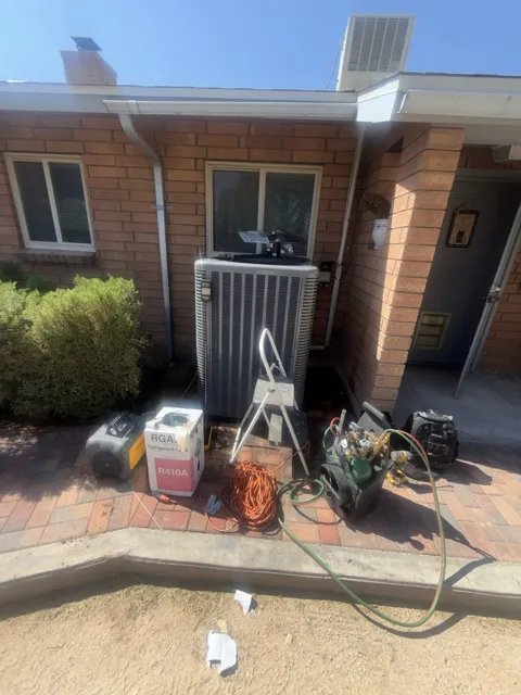Outdoor AC unit with hoses and service equipment nearby