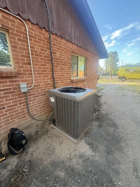 Outdoor air conditioning condenser beside a brick building
