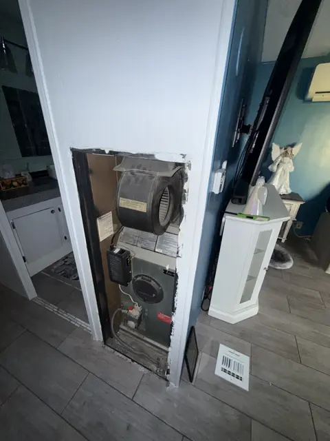 An indoor HVAC unit exposed through an open wall during work.