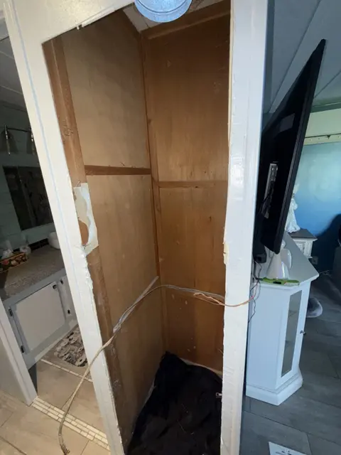 An empty equipment closet during work, with the wall opening and interior visible.