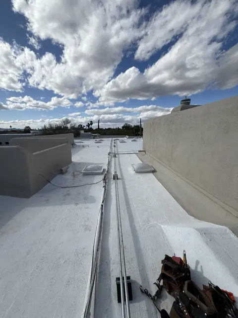 Conduit running across a flat roof, with tools nearby.