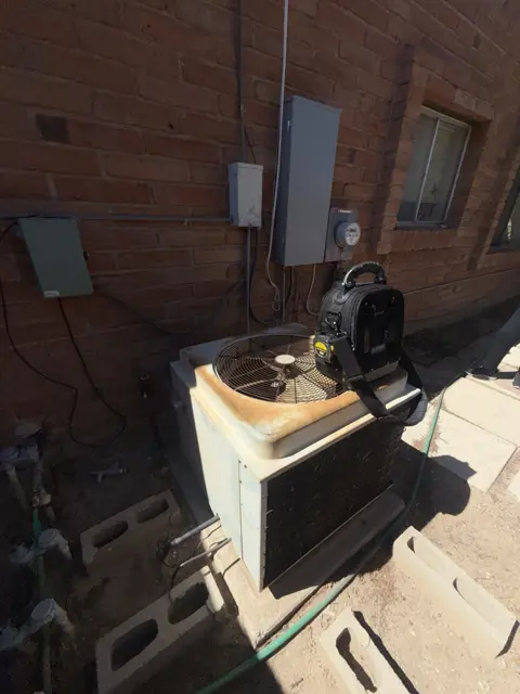 An outdoor cooling unit with its cabinet open and service equipment nearby.