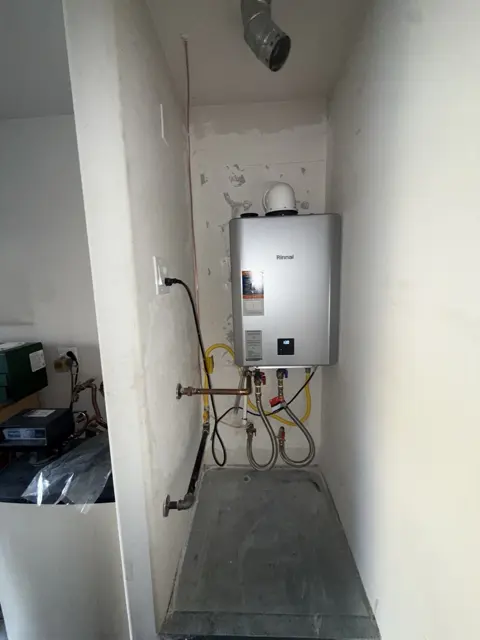 A tankless water heater and its piping in a utility space.