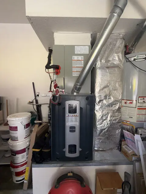 Indoor HVAC equipment and duct connections in a garage utility area.