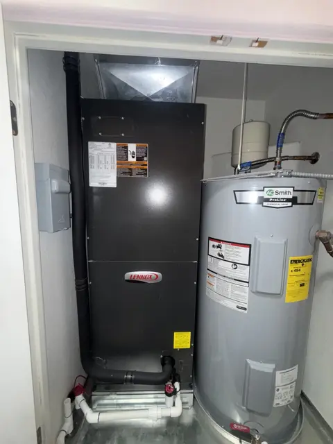 Indoor HVAC equipment beside a tank water heater in a utility closet.