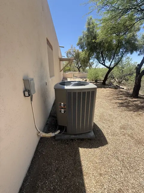An outdoor air conditioning unit on a pad beside a stucco home.