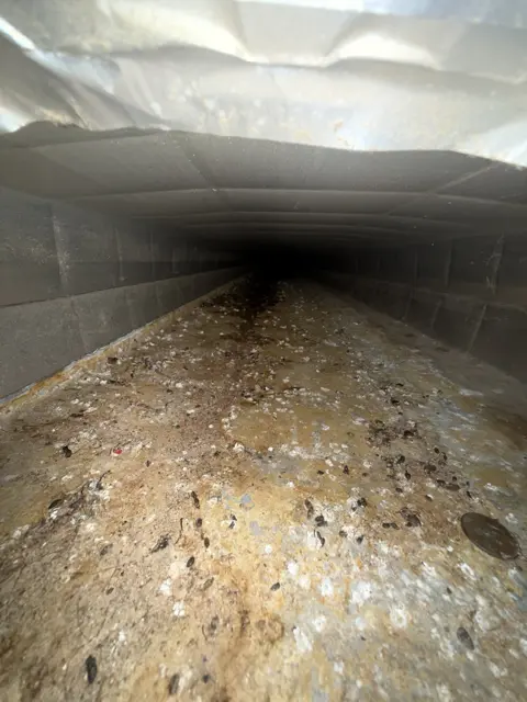 An interior duct view showing accumulated debris during a service visit.