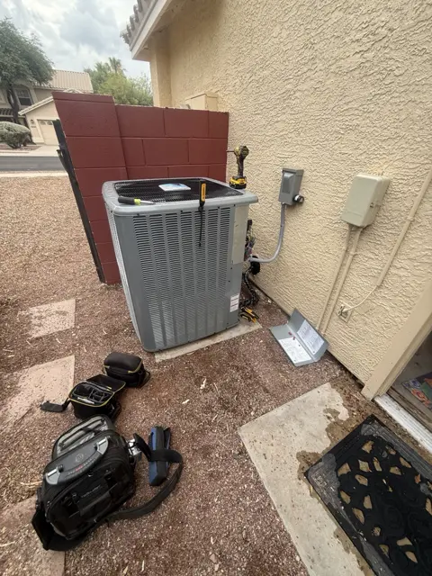 An outdoor condenser with tools arranged nearby for service.