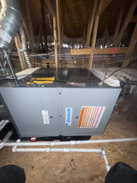 A horizontal indoor HVAC unit beneath attic framing.