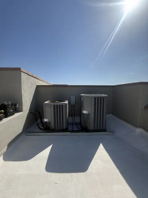 Two outdoor HVAC units positioned together on a flat roof.