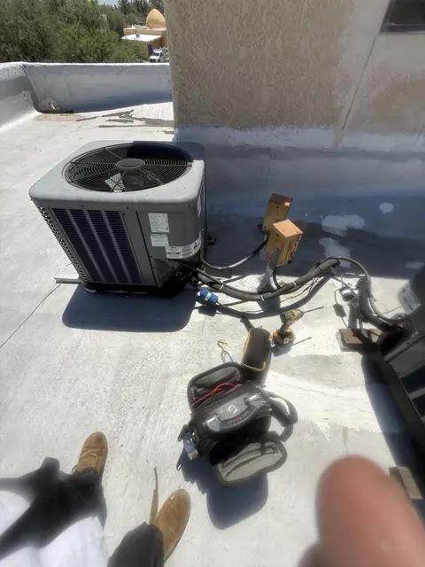 Service tools and hoses beside an outdoor unit on a flat roof.